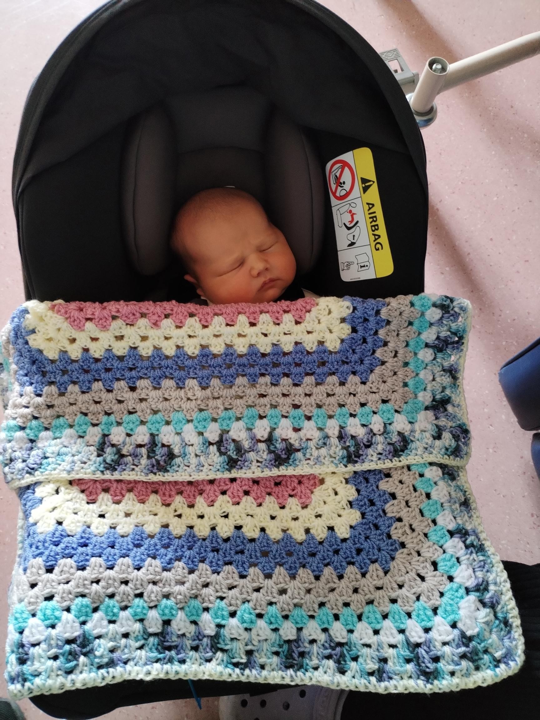 Baby Leo Thwaites with knitted blanket.