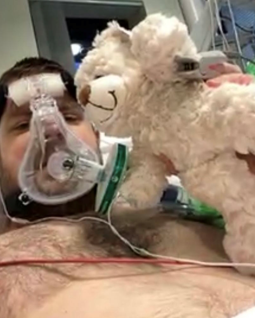 Laurence as a patient in the Intensive Care Unit at Warrington Hospital. Laurence is holding a recordable bear which has a message from his family.