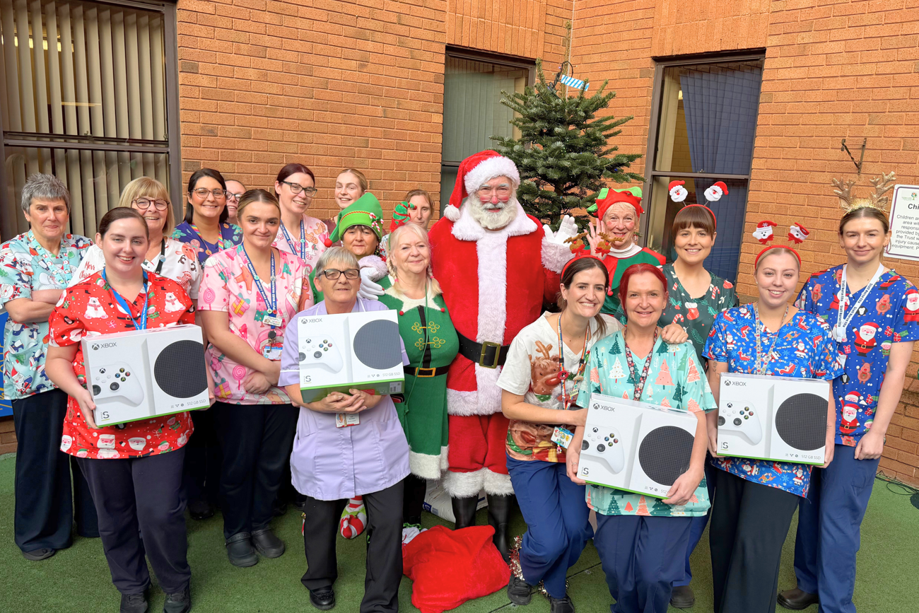 Staff posing with 4 donated Xboxes