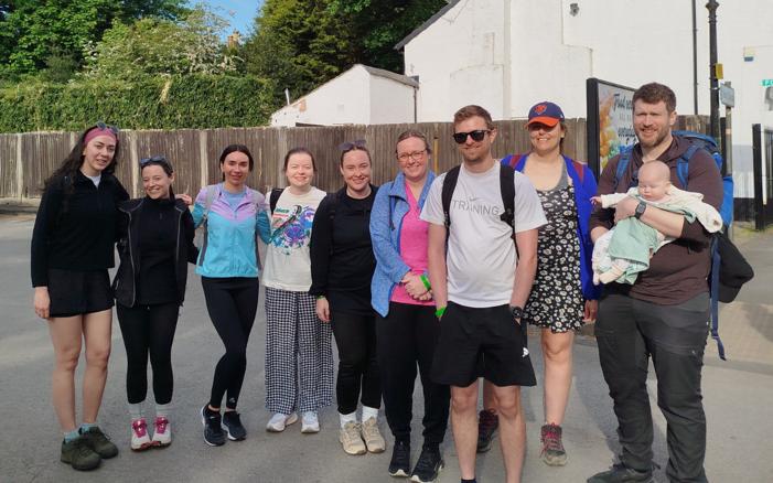 Nine members of the Ophthalmology Department and a baby smiling at the start of a 42km walking challenge.
