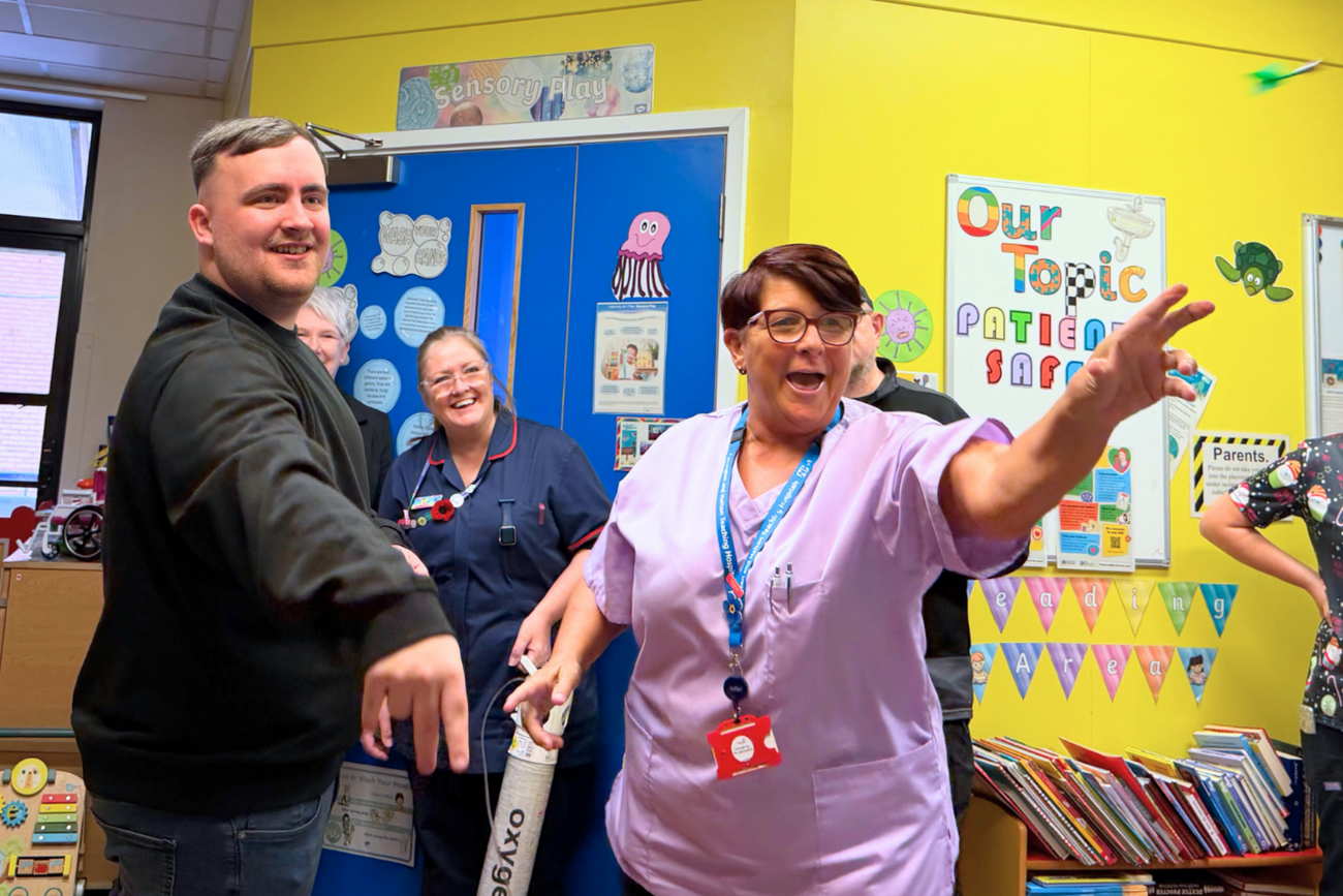 Luke Littler playing darts with staff