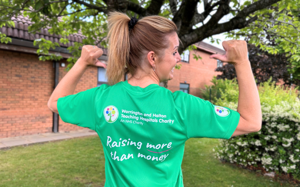 Fundraiser pointing to their T-shirt which is a green WHH Charity fundraising T-shirt.